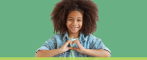 Black teen girl making a heart with her hands for World Kindness Day.