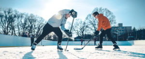 Two teen boys outside playing hockey for winter wellness.
