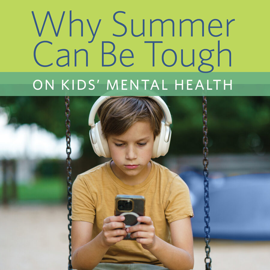 Young boy playing on phone while sitting on a swing outside in the summer.