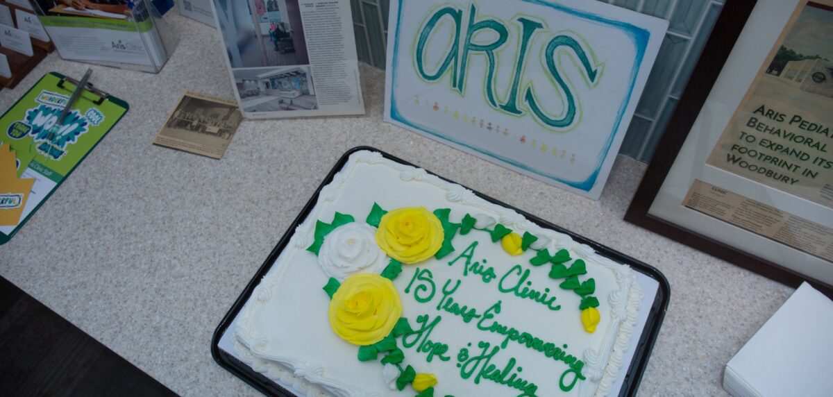 Aris Clinic 15-year anniversary cake displayed alongside memorabilia highlighting the clinic’s history.